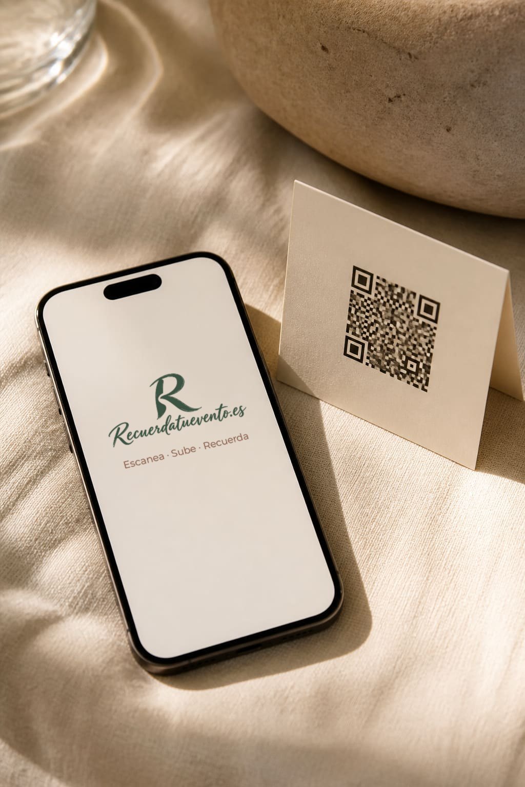 Móvil con el logo de Recuerdatuevento junto a una tarjeta con código QR.